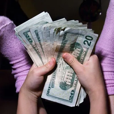 A kid holding a handful of $20 bills
