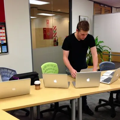 A man working from 4 laptops 