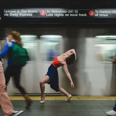 Women dancing in front of a train in the New York subway