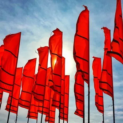 Lots of long red flags against a sunny blue sky