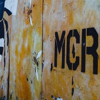 Spray paint on a wall of bees and "MCR" for Manchester.