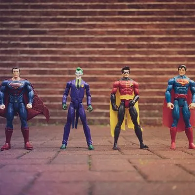 Small superhero and villains figurines in front of a brick wall