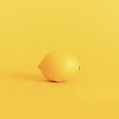 Photo of a whole lemon against a yellow background.