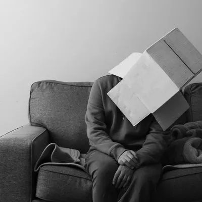 a person sitting on a couch with a box on their head