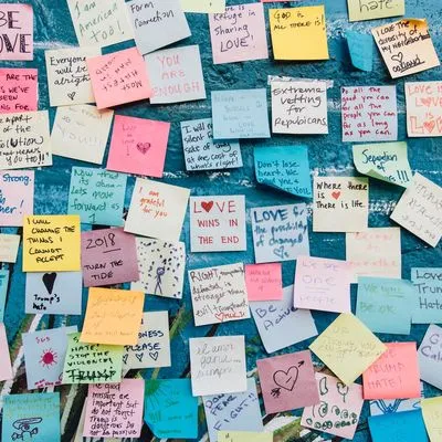Lots of different post it notes all with different messages written on them by different people.