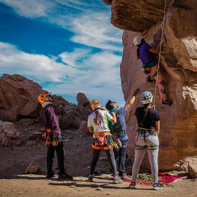 A group of people holding the rope for a rock climber 