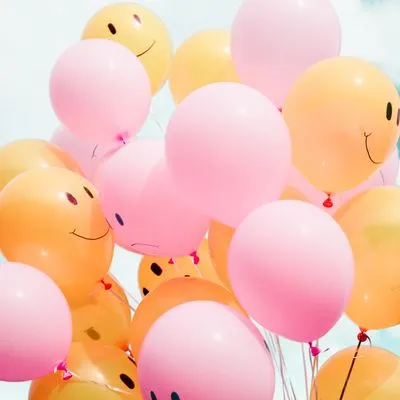 A bunch of pink and orange balloons with happy and sad faces on them.