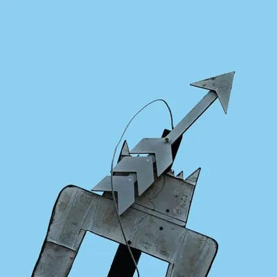 A metal sculpture of an arrow pointing skyward.
