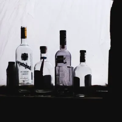 Four clear glass bottles in dim light