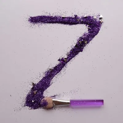 The letter Z made out of purple glitter with a makeup brush.